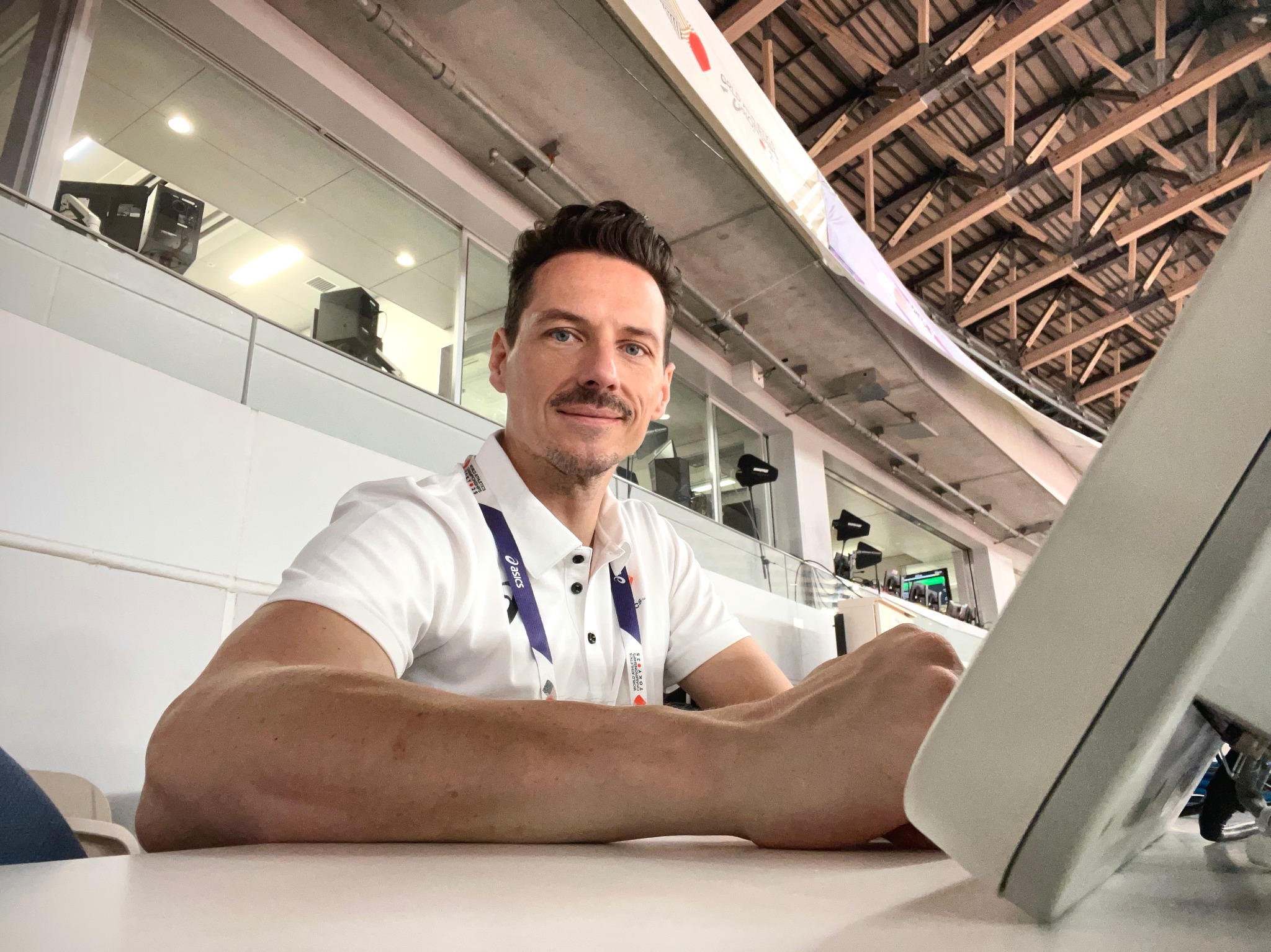 Jon Mulkeen working at his laptop in a stadium media tribune
